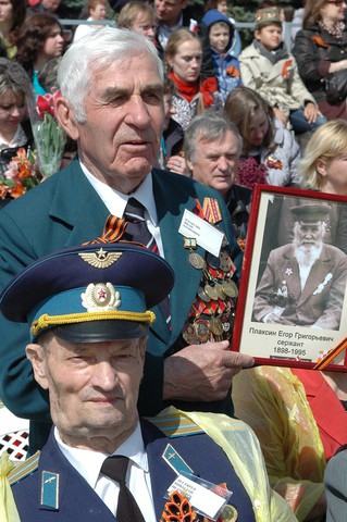 Трибуна ветеранов. В руках у участника Великой Отечественной войны  Ивана Егоровича Плаксина портрет отца